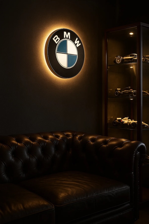 Runde BMW-Logo LED-Lampe in schwarz weiss blau in einem dunklen Zimmer รผber einer Ledercouch neben einer Vitrine