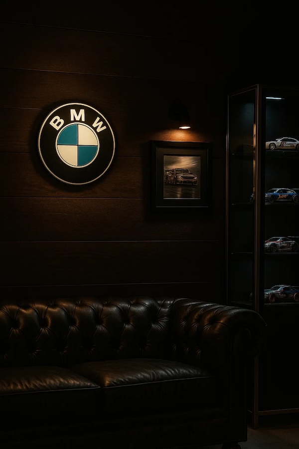Runde BMW-Logo LED-Lampe in Farbe in einem dunklen Zimmer รผber einer Ledercouch neben einer Vitrine