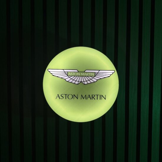 Beleuchtete Aston Martin LED-Lampe in grün an der Wand mit farblicher Ambiente-Beleuchtung