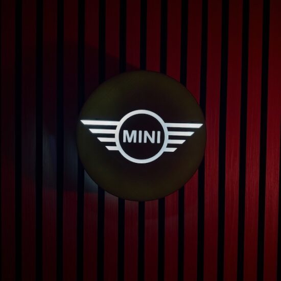 Beleuchtete MINI Logo LED-Lampe in grün weiß an der Wand mit farblicher Ambiente-Beleuchtung