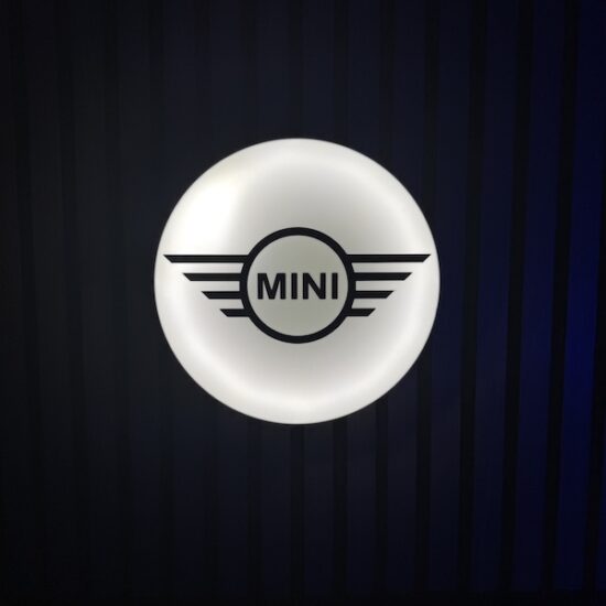 Beleuchtete MINI Logo LED-Lampe in schwarz weiß an der Wand mit farblicher Ambiente-Beleuchtung