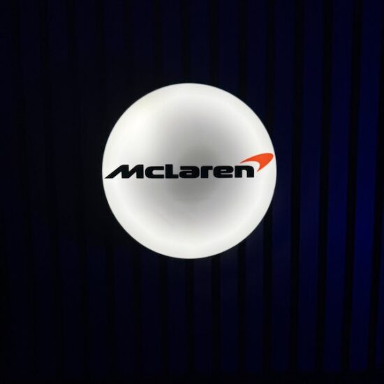 Beleuchtete McLaren Logo LED-Lampe in schwarz weiß an der Wand mit farblicher Ambiente-Beleuchtung
