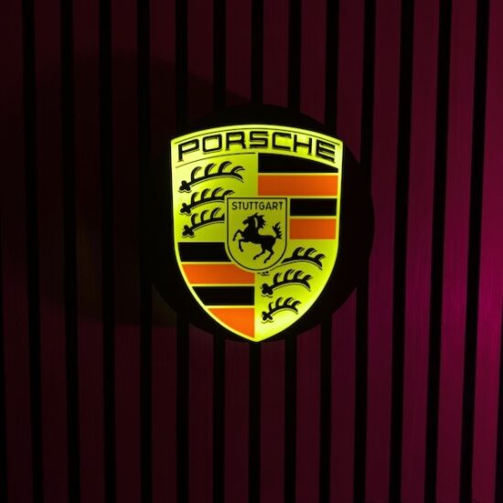 Beleuchtete Porsche Logo LED-Lampe in gelb schwarz rot an der Wand mit farblicher Ambiente-Beleuchtung